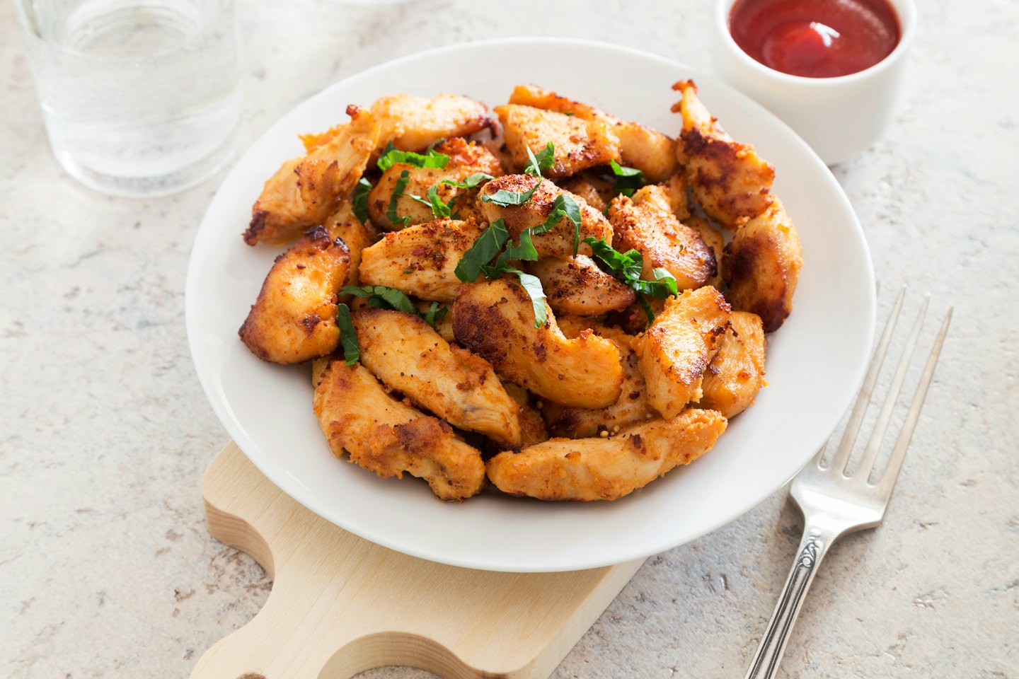 Golden-brown chicken pieces with herbs on a plate with sauce.