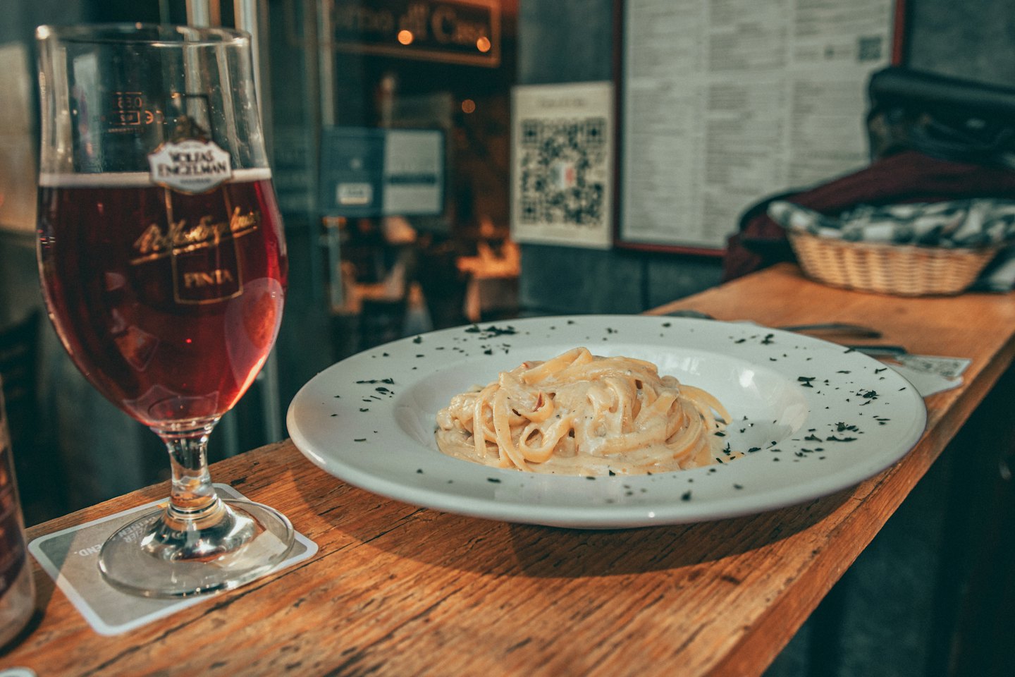 Creamy pasta garnished with herbs next to a red drink.